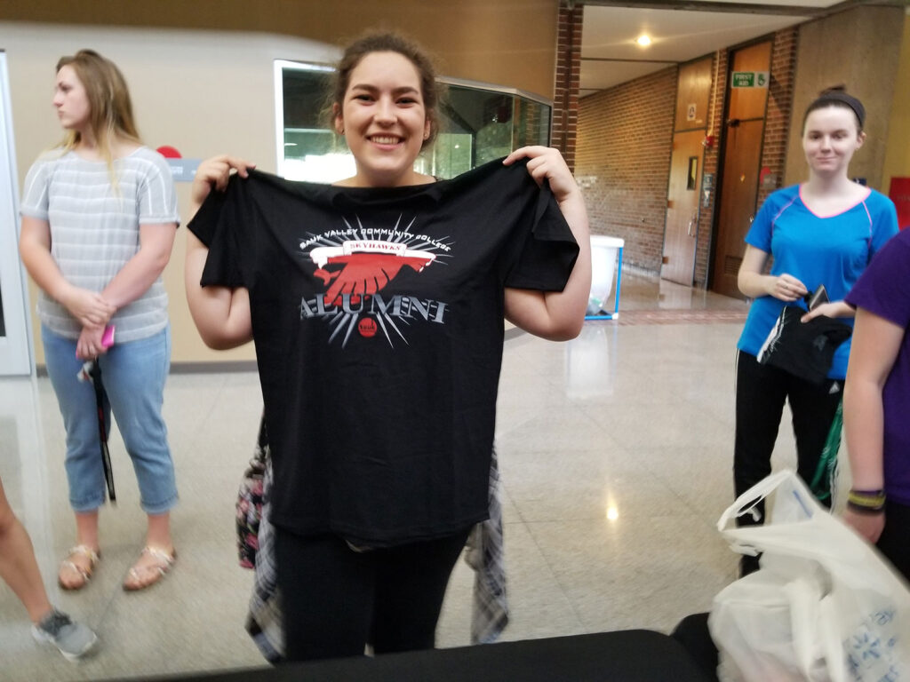 Alum holding an alumni shirt